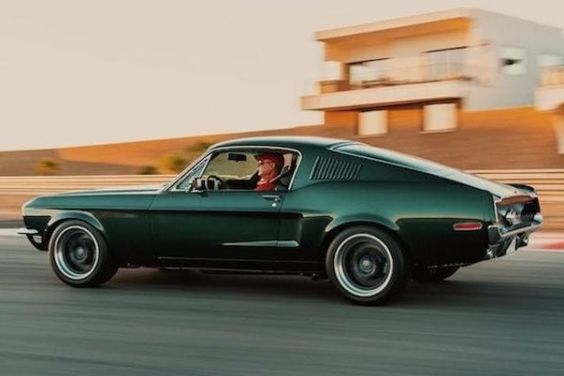 A man driving a vintage muscle car.